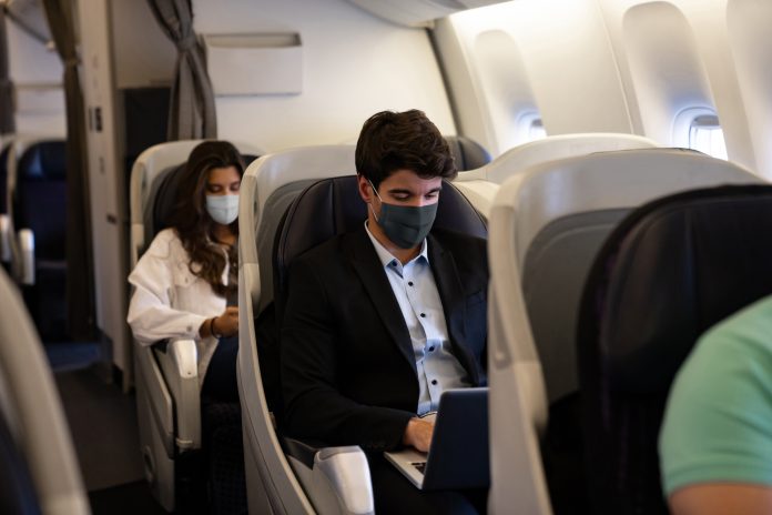 Business man traveling and wearing a facemask on the plane