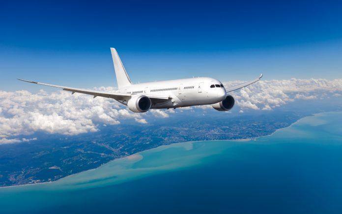 White,Passenger,Wide-body,Plane.,Aircraft,Is,Flying,In,Blue,Cloudy